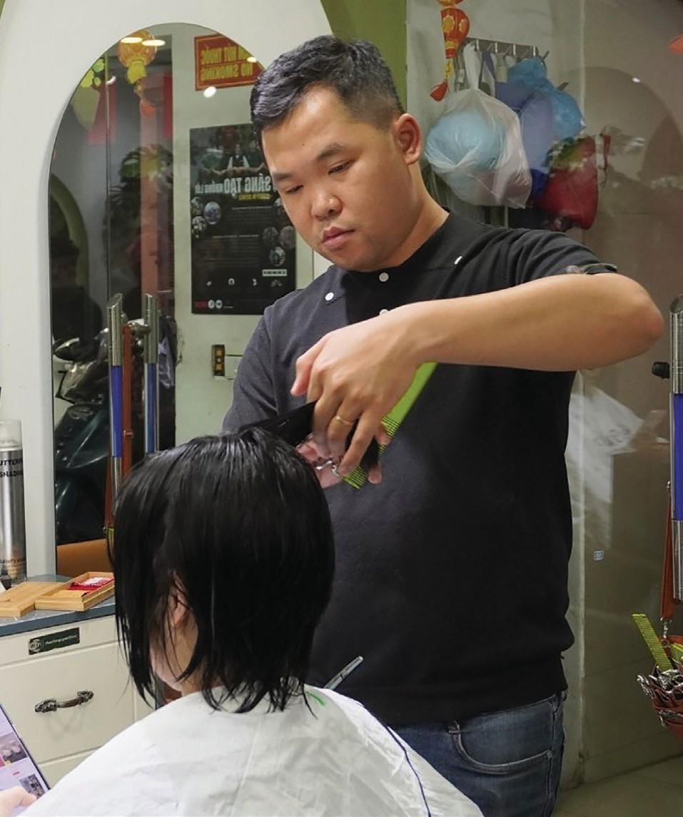 Thành Nguyễn cắt tóc cho khách với sự tập trung cao độ. Đôi tay nhanh, chắc và dứt khoát thay cho mọi lời nói.