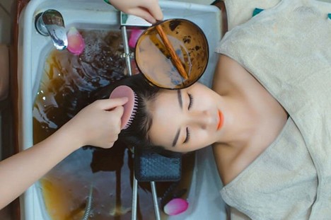 Gội đầu sạch với nước ấm sau khi dùng mỡ lợn để xử lý tóc khô xơ.